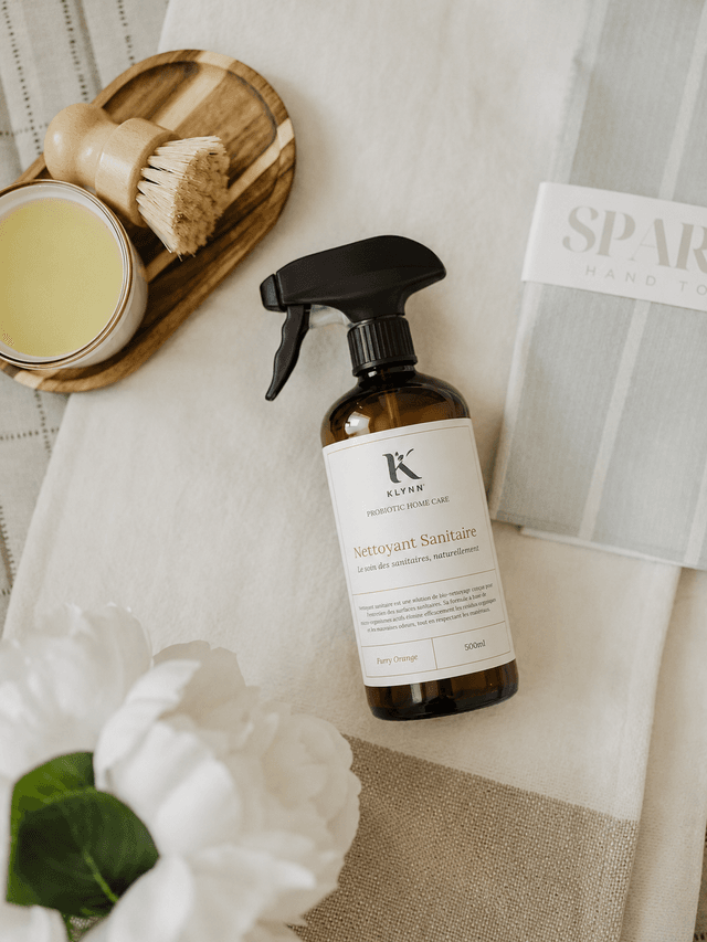 Nettoyant Klynn posé sur du lin, avec une brosse en bois et une bougie — composition premium